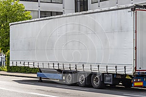 Semitrailer with white tarpaulin without inscriptions, standing on the street.