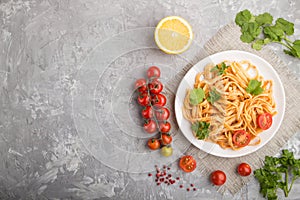 Semolina pasta with tomato pesto sauce, orange and herbs on a gray concrete background. Top view, copy space