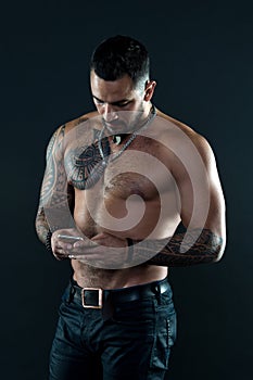 Send message. Handsome fit man send message smartphone. Muscular tattooed athlete look attractive. Messaging