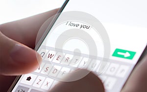 Sending I love you text message with mobile phone. Online dating, texting or catfishing concept. Romance fraud, scam. photo