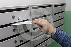Sending mail, a man puts a letter in the mailbox. Placing letters in the mailbox of an apartment building, close-up. Russia