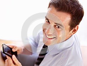 Sending a text to a valuable client. Smiling young businessman sending a text message.