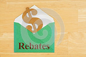 Rebates text with dollar sign symbol with green envelope on textured wood desk