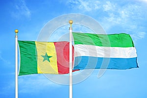 Senegal and Sierra Leone two flags on flagpoles and blue cloudy sky