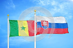 Senegal a Slovensko dve vlajky na stožiaroch a modrá zamračená obloha