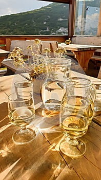 Senes - Homemade white wine in a white carafe with a few glasses, placed on a wooden table in a mountain cottage in Dolomites
