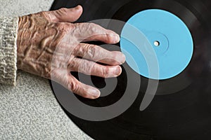 Senile hand is on vinyl LP. Close-up of the old man or old woman hand.