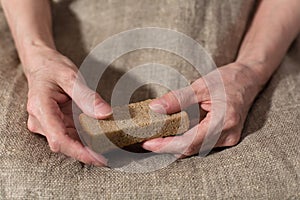 Senile hands hold a slice of rye bread