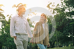 Senior active caucasian couple holding hands looks happy and carefree in the park in the afternoon autumn sunlight with copy space