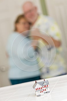 Senior Adult Couple Gazing Over Small Model Home on Counter