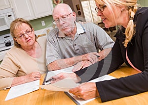 Senior Adult Couple Going Over Documents in Their Home with Agent At Signing