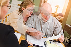 Senior Adult Couple Going Over Documents in Their Home with Agent At Signing