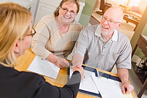 Senior Adult Couple Going Over Documents in Their Home with Agent At Signing