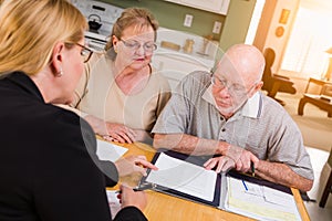 Senior Adult Couple Going Over Documents in Their Home with Agent At Signing