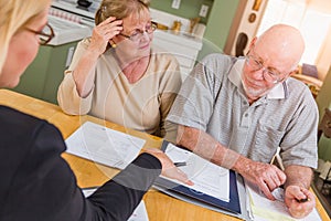 Senior Adult Couple Going Over Documents in Their Home with Agent At Signing