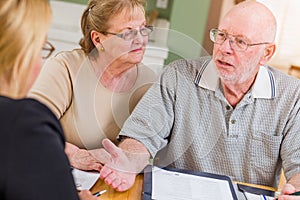 Angry Senior Adult Couple Going Over Documents in Their Home with Agent At Signing