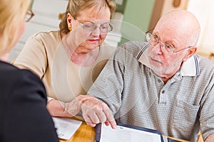 Senior Adult Couple Going Over Documents in Their Home with Agent At Signing