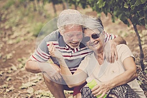 Senior adult couple laugh in happines together forever playing with soap bubbles in the country yard outdoor leisure activity.