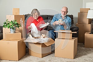 Smiling Senior Couple Packing or Unpacking Moving Boxes photo