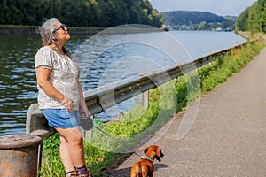 Senior adult female tourist together with her dachshund taking a break next to Albert canal