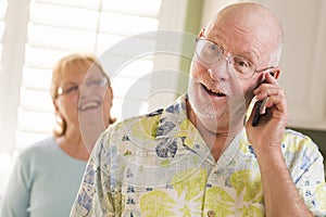 Senior Adult Husband on Cell Phone with Wife Behind