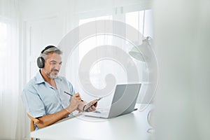 Senior adult Man in headphones using digital tablet and laptop