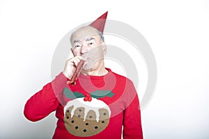 Senior adult man wearing Christmas jumper blowing party blower photo