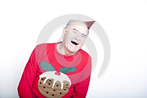 Senior adult man wearing a Christmas jumper and a red party hat photo