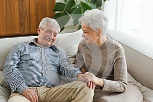 Senior adult mature couple in love holding hands at home. Mid age old husband and wife looking with tenderness love