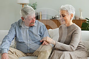 Senior adult mature couple in love holding hands at home. Mid age old husband and wife looking with tenderness love