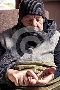 Senior adult or pensioner is sitting with winter clothes indoors