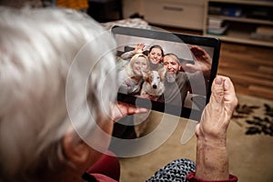 Senior adult is talking via video conference with her family