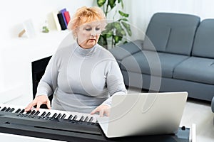 Senior adult woman in active retirement living plays the piano in her home.