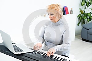 Senior adult woman in active retirement living plays the piano in her home.