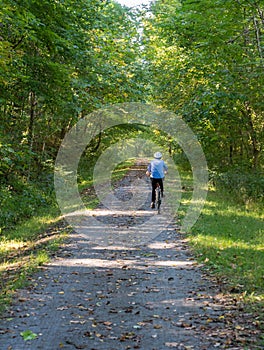 Senior adult woman cycles away from camera