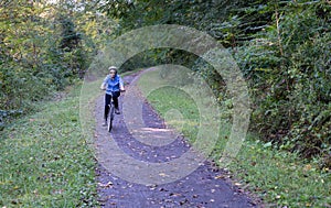 Senior adult woman cycles towards camera