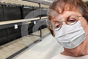 Senior Adult Woman In Medical Face Mask Walking Down Empty Aisle of Grocery Store