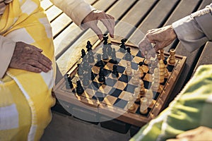 Senior adult women playing chess on the bench outdoors in the park. Close up