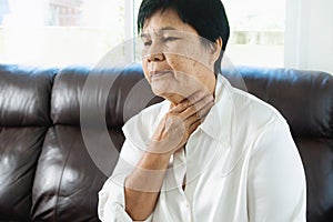 Senior adult women touching the neck feeling unwell coughing with sore throat pain.Healthcare and medicine concept