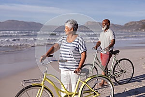 Senior african american couple with bicycles standing on the beach