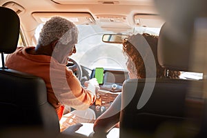 Senior African American Couple On Drive Through Countryside Using Sat Nav On Mobile Phone