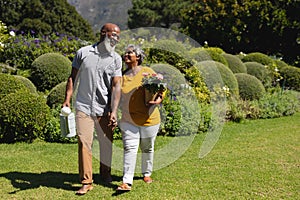 Senior african american couple spending time in sunny garden together walking and smiling