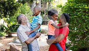 Senior African American couple spending time in their grandson and granddaughter in the garden