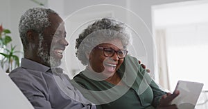 A senior african american couple spending time together at home laughing social distancing in quaran