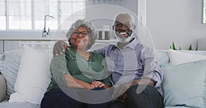 A senior african american couple spending time together at home smiling at the camera social distanc