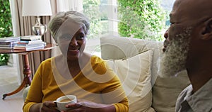 Senior african american couple talking and drinking tea in living room at home