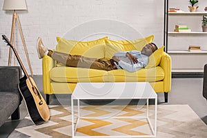 senior african american man sleeping on yellow couch