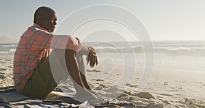 Senior african american man wearing shirt and sitting on sunny beach