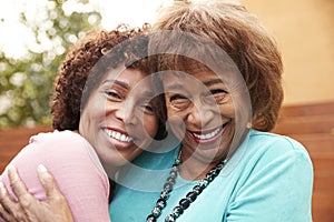 Senior African American  mum and her middle aged daughter smile to camera embracing, close up photo