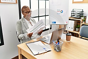 Senior african american woman business worker reading paperwork working at office